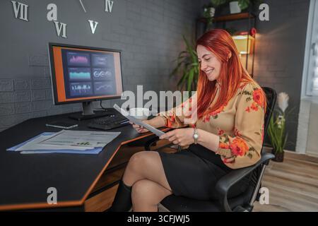 Donna d'affari che analizza i rapporti finanziari e lavora al computer in ufficio Foto Stock