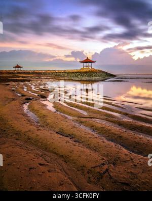 Mentre il sole sorge all'orizzonte, il Pantai Sanur di Bali si trasforma in uno spettacolo mozzafiato. Foto Stock