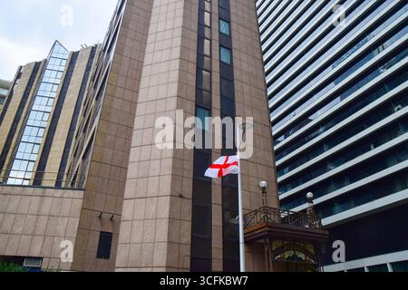 Londra, Regno Unito. 23 agosto 2025. Si vede una bandiera inglese legata ad un lampione fuori dal Britannia International Hotel a Canary Wharf, dove sono ospitati i richiedenti asilo. Le bandiere inglesi appaiono sempre più spesso sulle strade e sui lampioni in tutta l'Inghilterra nel bel mezzo dell'attuale ondata di proteste contro il collocamento di migranti e richiedenti asilo negli hotel. Credito: SOPA Images Limited/Alamy Live News Foto Stock