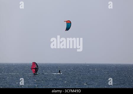 Cabedelo, Viana do Castelo, Portogallo - 21 agosto 2025: Varietà di attività di surf sulla spiaggia dell'Oceano Atlantico, kitesurf, windsurf Foto Stock