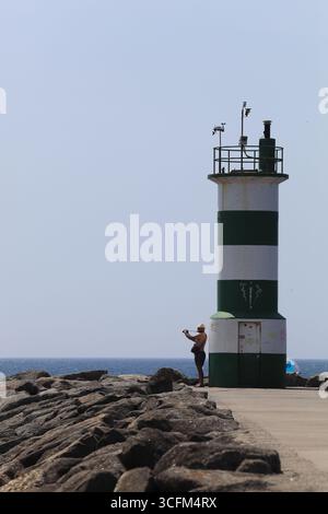 Cabedelo, Viana do Castelo, Portogallo - 21 agosto 2025: Un uomo che scatta foto vicino al faro dell'Oceano Atlantico Foto Stock