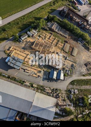 Società di costruzioni che costruiscono case in legno con gru catturate dalla vista aerea Foto Stock