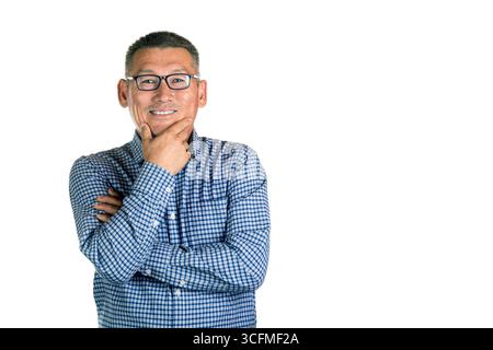 Uomo asiatico sorridente di mezza età con occhiali che tengono il mento isolato su sfondo bianco. Foto Stock