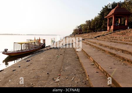 Barche tradizionali in legno locali sul fiume Mahanadi e persone che si godono nel giardino con vista sul fiume a Shivrinarayan, sito di pellegrinaggio, Chhattisgarh, India Foto Stock