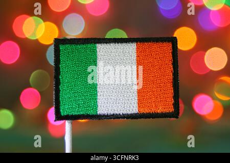 Patch ricamata bandiera irlandese con sfondo bokeh arcobaleno, ideale per feste, Natale, Capodanno e feste nazionali. Foto Stock