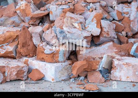 Un mucchio di vecchi mattoni rossi rotti. Macerie ruvide e intemprate da edifici demoliti. Rifiuti di mattoni di argilla rossa in decomposizione e sbriciolati. Det. Architettura Foto Stock