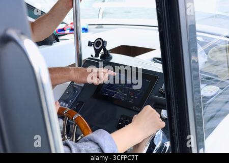 Vecchio capitano che insegna la navigazione marittima nella cabina di pilotaggio della barca a motore Foto Stock