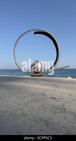 Una scultura metallica, parte della collezione d'arte pubblica sul lungomare di Limassol Molos, con il Mar Mediterraneo sullo sfondo. Foto Stock