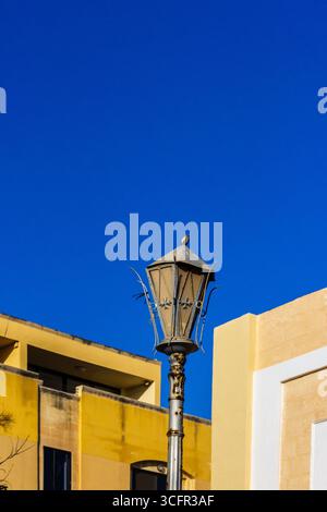 Lampada da strada rustica contro un cielo blu luminoso e un'architettura moderna Foto Stock