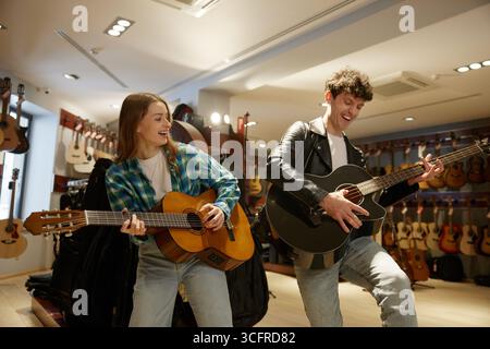 In un negozio di musica, un uomo e una donna suonano le loro chitarre abilmente Foto Stock