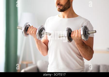 Closeup di bell'uomo bearded che fa workout dumbbell a casa Foto Stock