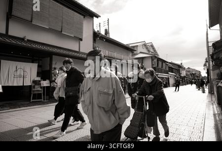 La folla cammina lungo una storica strada pedonale di Kyoto, con residenti anziani e turisti che si muovono insieme Foto Stock