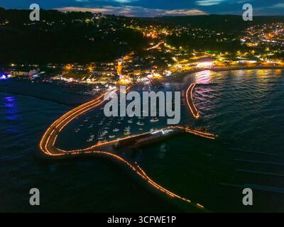 Lyme Regis, Dorset, Regno Unito. 24 agosto 2025. Vista aerea delle candele sulle illuminazioni Cobb presso la località balneare di Lyme Regis nel Dorset. Circa 5000 candele sono state accese lungo le storiche mura del porto di Cobb in memoria dei propri cari, che sono stati osservati da migliaia di spettatori nel Lister Garden e sul lungomare. I fondi raccolti saranno ripartiti tra le cause locali, il cancro alla prostata nel Regno Unito e il sostegno al cancro di Macmillan. Crediti fotografici: Graham Hunt/Alamy Live News Foto Stock