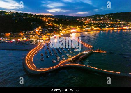 Lyme Regis, Dorset, Regno Unito. 24 agosto 2025. Vista aerea delle candele sulle illuminazioni Cobb presso la località balneare di Lyme Regis nel Dorset. Circa 5000 candele sono state accese lungo le storiche mura del porto di Cobb in memoria dei propri cari, che sono stati osservati da migliaia di spettatori nel Lister Garden e sul lungomare. I fondi raccolti saranno ripartiti tra le cause locali, il cancro alla prostata nel Regno Unito e il sostegno al cancro di Macmillan. Crediti fotografici: Graham Hunt/Alamy Live News Foto Stock