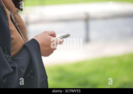 Persona che utilizza lo smartphone mentre è in piedi sull'erba verde Foto Stock