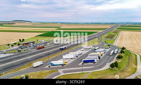 Vista aerea dell'area di sosta autostradale con parcheggio per camion, camion in fila, infrastruttura autostradale Foto Stock