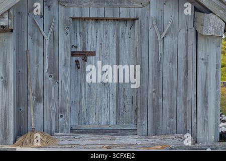 Dispositivo di chiusura in metallo su porta in legno grigio resistente agli agenti atmosferici. Legname naturale invecchiato nel tempo, mettendo in risalto texture, patina e artigianato rustico nordico nell'arcipite rurale Foto Stock