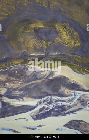Vista aerea dei tortuosi fiumi glaciali che attraversano terreni aspri e contrastanti di sabbia vulcanica scura e muschio verde brillante, Highlands, Islanda. Foto Stock