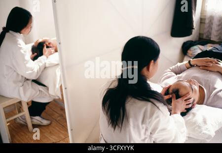 Massaggiatori femmina facendo massaggio testa a clienti in Cina Yunnan Foto Stock