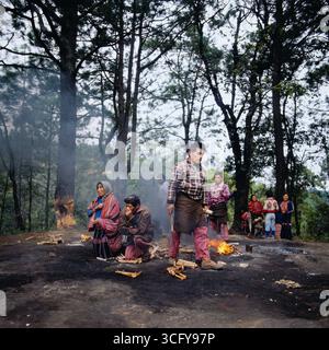 Mehrere Personen entzünden zeremonielle Feuer auf einer bewaldeten Lichtung, vermutlich im Rahmen eines traditionellen Maya-rituals. Guatemala, um 1980. Foto Stock