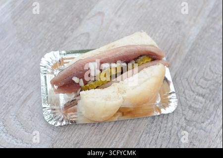 Il «Herring Sandwich» (Broodje Haring) è una prelibatezza olandese con panino bianco e aringhe crude salate, cetriolini a fette e cipolle a dadini, servito freddo Foto Stock