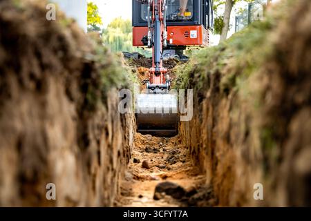 Benna da miniescavatore in una trincea in un cantiere edile Foto Stock
