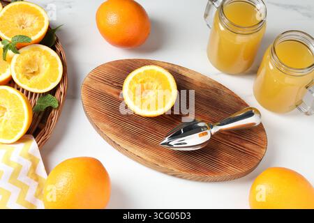 Succo d'arancia appena spremuto, frutta e centrifuga sul tavolo bianco, vista dall'alto Foto Stock