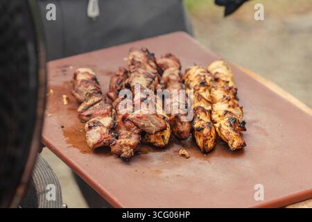 Succosa carne spiedata grigliata su una tavola e pronta da mangiare durante il barbecue con affumicatura Foto Stock