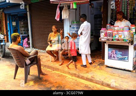 Famiglia locale con colori sui volti che celebrano il festival holi, festival dei colori che si trova vicino a un negozio di strada, mumbai, india, polvere sul pavimento Foto Stock