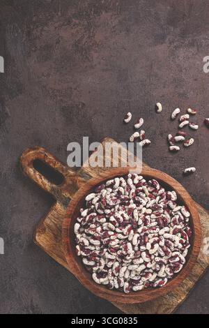 Fagioli variegati, rossi con macchie bianche, crudi in una ciotola di legno, vista dall'alto, nessuna gente Foto Stock