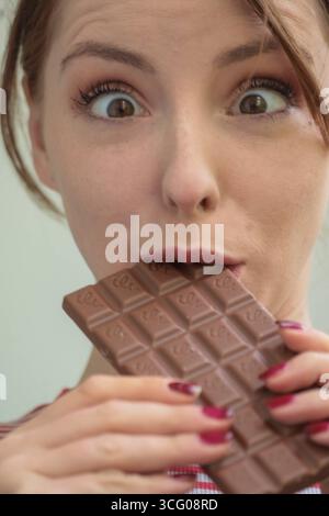 junge frau beißt mit genuss und lächeln in eine tafel schhokolade junge frau beißt mit genuss und lächeln in eine tafel schhokolade *** giovane donna morde in una barretta di cioccolato con piacere e un sorriso giovane donna morde in una barretta di cioccolato con piacere e un sorriso Foto Stock