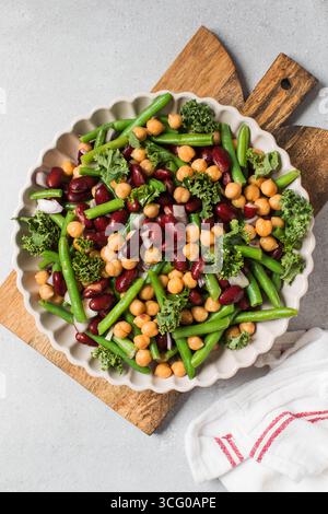 Insalata di verdure fresche con fagioli verdi, ceci, cavoli e fagioli rossi su tavola di legno Foto Stock