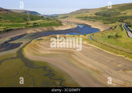La vista aerea con droni cattura la dura realtà della grave siccità nel lago artificiale Woodhead vicino a Glossop, rivelando vaste distese di terra secca e incrinata. Foto Stock