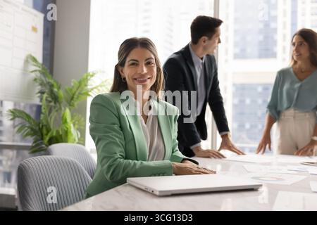Ritratto di una donna d'affari sorridente alla macchina fotografica, seduta al tavolo di una conferenza Foto Stock