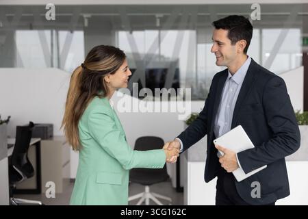 Uomo e donna professionisti che stringono la mano in un ufficio moderno Foto Stock