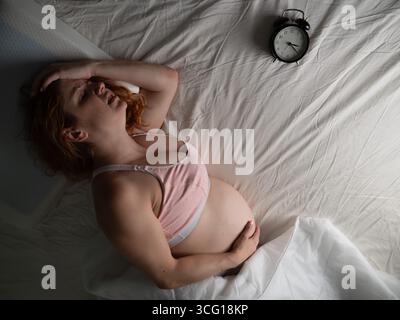 La donna incinta soffre di dolore di notte. Foto Stock