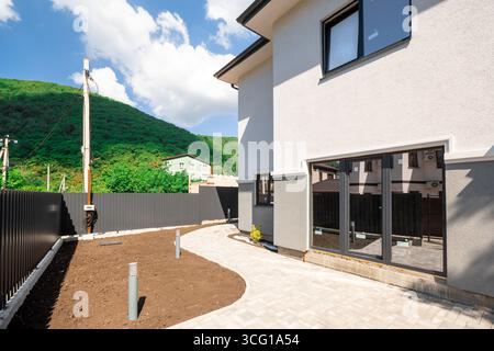 Una casa con una grande finestra sul davanti. La finestra è incorniciata in nero e ha un bordo rosso. La casa si trova su una collina Foto Stock