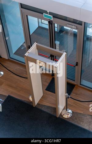 Porte automatiche all'ingresso di un edificio moderno con rilevatore di metalli di sicurezza per accesso controllato e pubblica sicurezza. Foto Stock