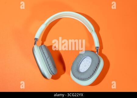 Eleganti cuffie audio appoggiate su uno sfondo verde brillante, che rappresentano la musica, l'ascolto di podcast o la produzione audio Foto Stock