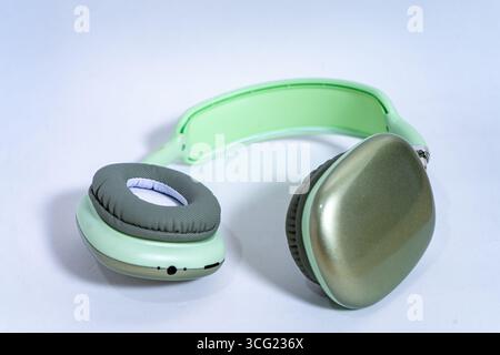 Eleganti cuffie wireless color verde pastello isolate su uno sfondo bianco, che rappresentano musica, tecnologia e divertimento audio Foto Stock