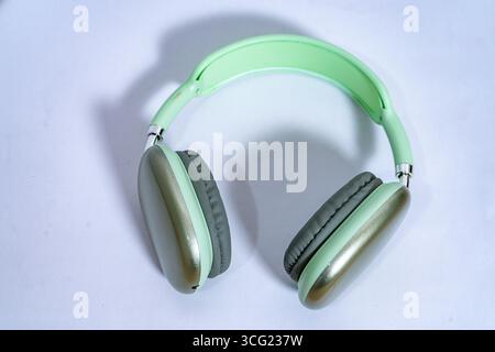 Eleganti cuffie wireless color verde pastello poggiate su una superficie bianca e pulita, che rappresentano musica, tecnologia e divertimento audio Foto Stock