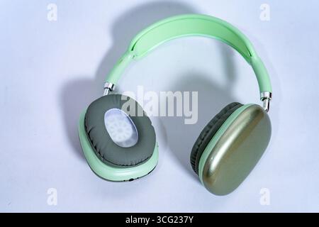 Eleganti cuffie wireless color verde pastello isolate su sfondo bianco e dotate di tecnologia audio moderna Foto Stock