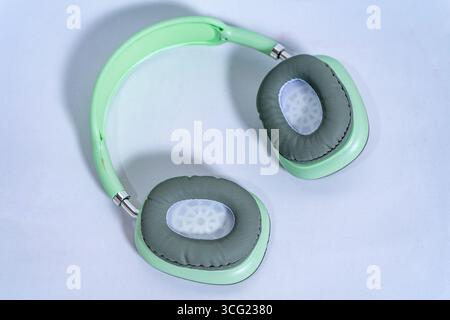 Eleganti cuffie verdi pastello con padiglioni grigi isolati su sfondo bianco, che rappresentano musica, podcast o audio Foto Stock
