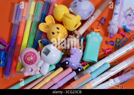 Articoli di cancelleria kawaii color pastello che creano un vivace appartamento per il ritorno a scuola su sfondo arancione Foto Stock