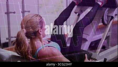 Spinge una donna in abbigliamento sportivo turchese che fa la pressa per gambe in palestra, con sovrapposizione di macchine e grafici Foto Stock