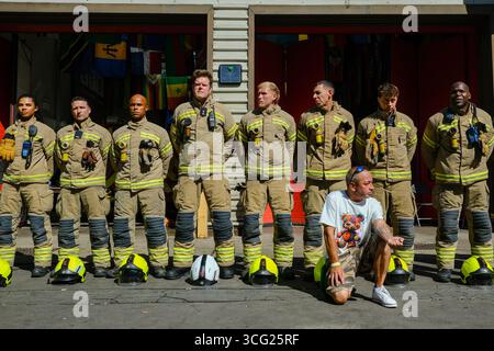 Londra, Regno Unito. 25 agosto 2025. I vigili del fuoco di base alla stazione dei vigili del fuoco di North Kensington hanno tenuto un minuto di silenzio in memoria dei 72 residenti morti nell'incendio della torre di Grenfell. Padre in lutto Ramiro Urbano, che ha tragicamente perso la figlia Jessica, si inginocchiò di fronte ai vigili del fuoco fuori dalla stazione, mostrando un tatuaggio dedicato a Jessie sul suo avambraccio. Credito: Fotografia dell'undicesima ora/Alamy Live News Foto Stock