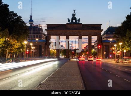Berlino, Germania. 26 agosto 2025. Le auto percorrono la Straße des 17. Juni sullo sfondo della porta di Brandeburgo al mattino, lasciando tracce di luce a causa della lunga esposizione. Credito: Soeren Stache/dpa/Alamy Live News Foto Stock