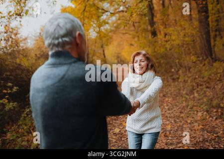 Coppia in pensione in piedi nel mezzo di colorati boschi autunnali. Foto Stock