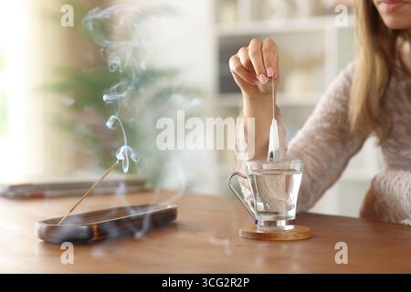 Primo piano ritratto di una donna che prepara il bastone di incenso che brucia il tè a casa Foto Stock