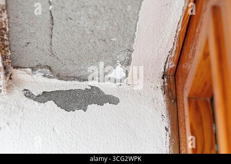 La rimozione della vernice su un soffitto rivela danni causati dall'acqua in prossimità di un telaio di legno della porta, indicando una potenziale perdita e la necessità di riparazioni Foto Stock